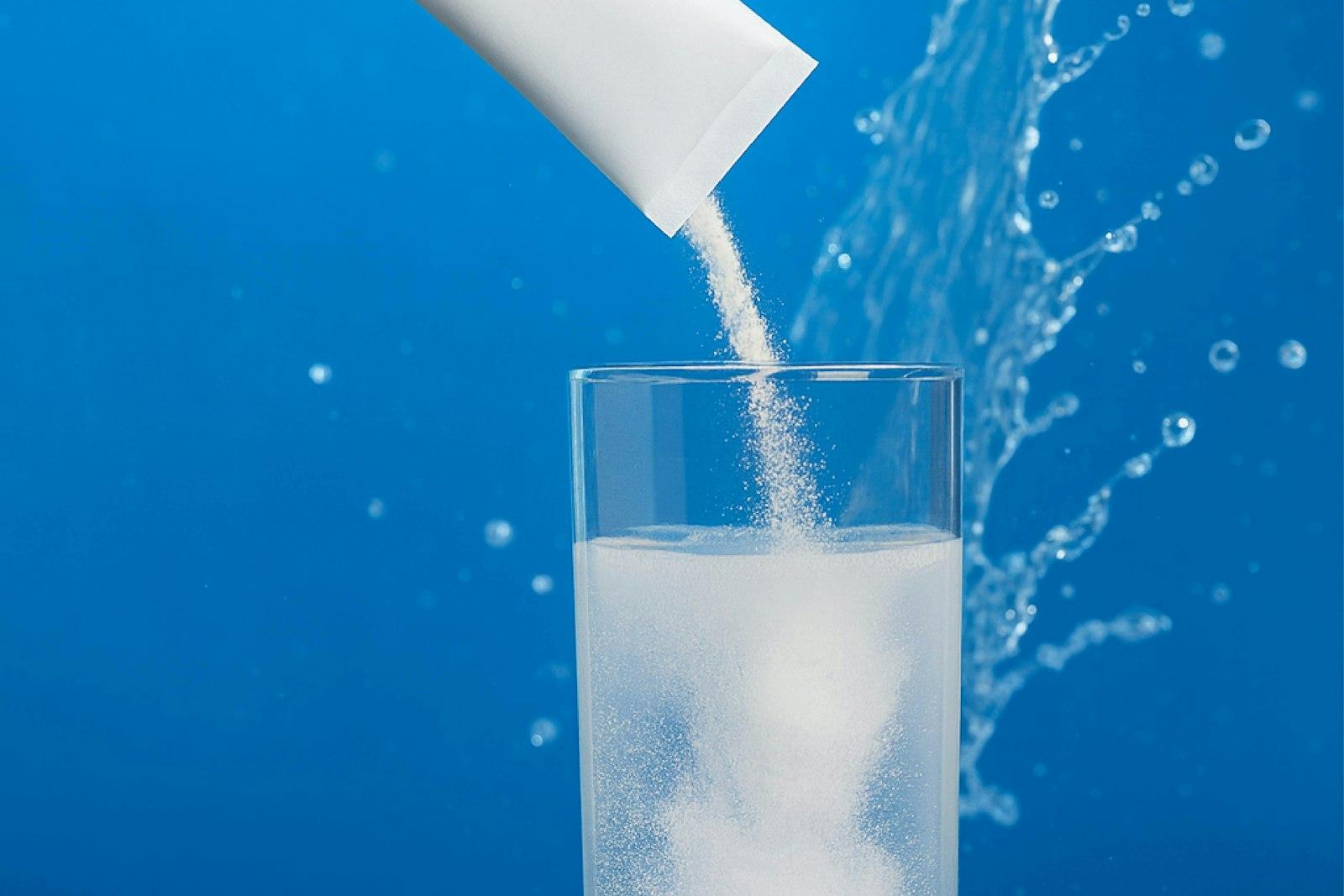 Powder pouring from a sachet into a glass of water